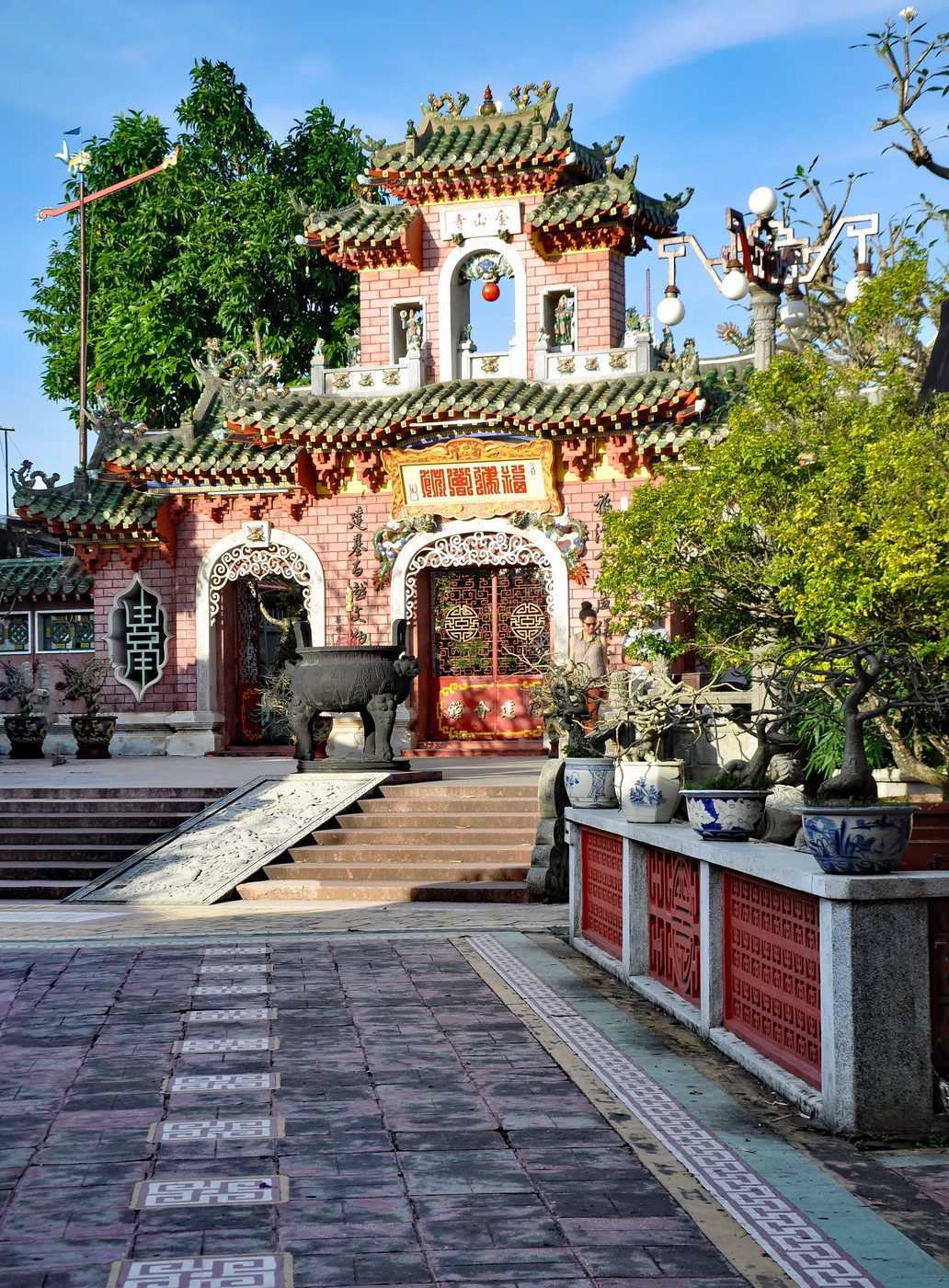 The gate of the Fujian hall in Hội An, three openings under curved tiled roofs, modelled dragons on the ridge, Chinese characters across the lintel.
