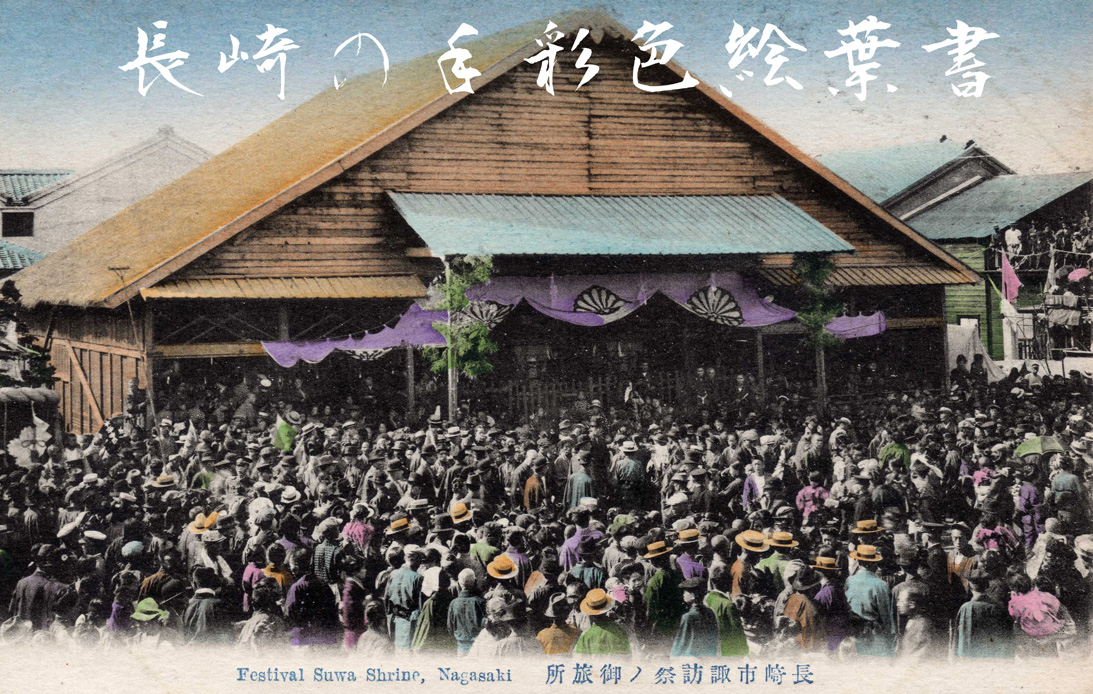 A hand-tinted postcard: a crowd in straw hats packed into the yard before a large thatched hall, purple curtains hung along its eaves. Japanese characters run across the top and a French line across the foot.